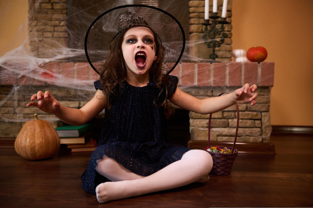 穿着女巫服装的小孩。万圣节派对。戴着巫师帽的可爱女婴。希望拼写。秋天的节日图片下载