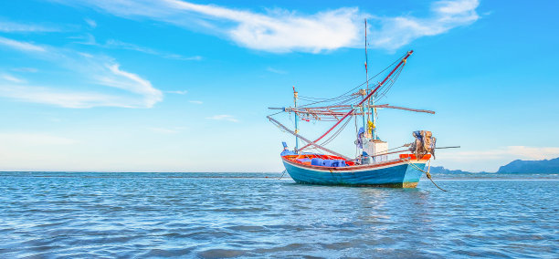 在美丽的碧海蓝天的清晨，一艘渔船停泊在海边。图片下载