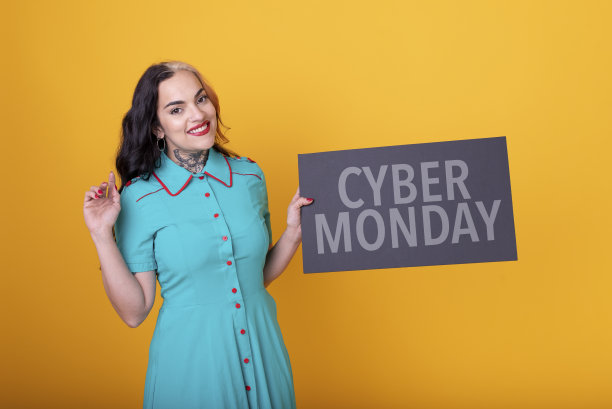 一个美丽的女人拿着一个黄色背景的网络星期一标志图片下载