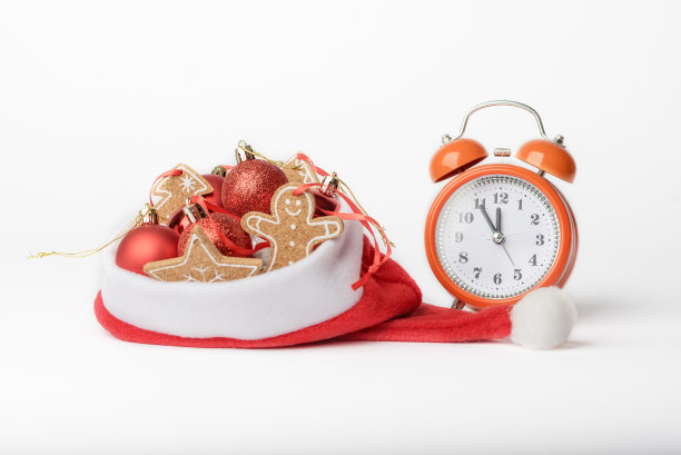 迎接新年的概念照片，闹钟和圣诞老人帽子上的圣诞树装饰图片下载