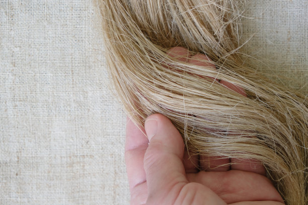 女子的手展示了大麻织物背景上天然大麻或亚麻的纤维。图片下载