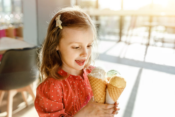 快乐的宝宝，在一个炎热的阳光灿烂的日子里，手里拿着几个冰淇淋球图片下载