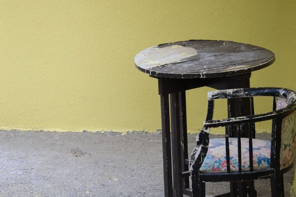 旧的木制圆桌和一把椅子，放在混凝土地面和墙壁的房间里图片下载