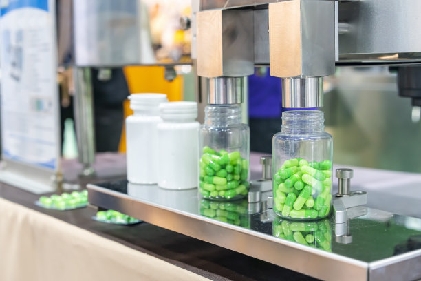 药用胶囊自动灌装计数机在生产过程中，将透明塑料瓶封闭在喷嘴分配器组件下图片下载