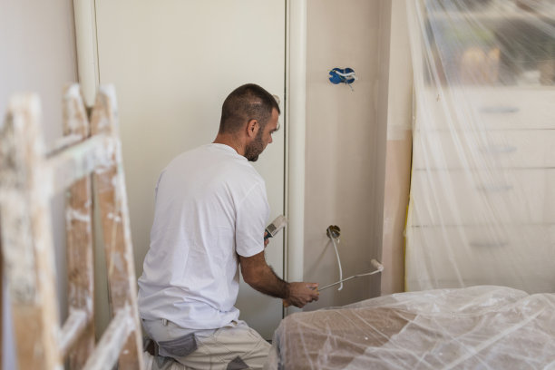 房屋油漆工专注于刷门边的墙图片下载