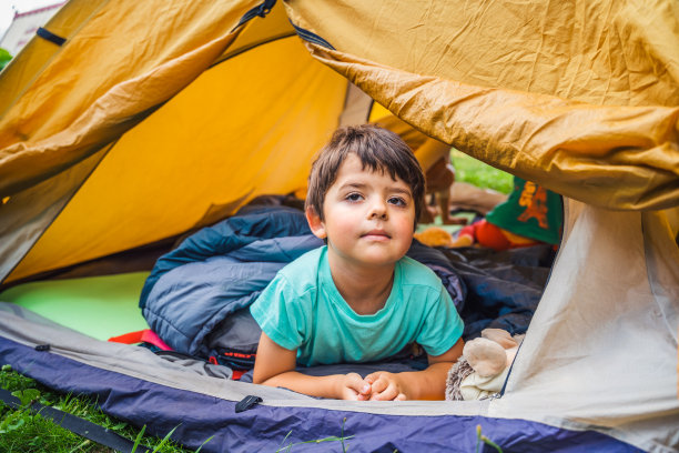 小孩，小孩，男孩玩耍，睡在橙色旅游帐篷的睡袋里。家庭旅行，远足大自然。后院游戏，玩得很开心。户外休闲活动。自组装，搭建露营帐篷图片下载