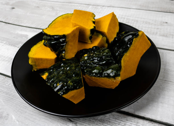 南瓜或杰瑞姆切成小块，放在木制背景的黑色盘子上。来自葫芦科和葫芦属，富含维生素，常用于制作糖果和瓜泥。图片下载