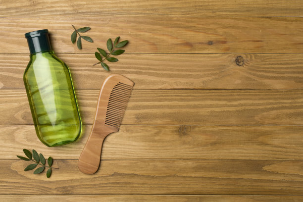 用草药提取的洗发水和梳子在木制背景，俯视图图片下载