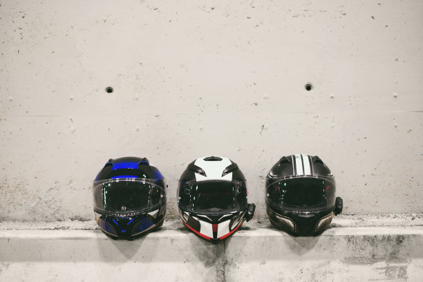 混凝土背景上的三个摩托车头盔。图片下载