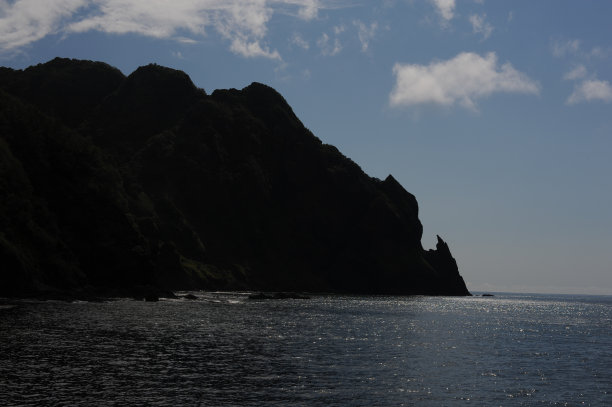 阳光明媚的日子里，岩石和海滩的如画海滨，天空湛蓝，海洋平静，位于日本北部北海道室兰的伊丹木海滩图片下载