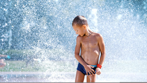 兴奋的七岁男孩，在一个炎热的夏天，在喷水之间，在喷泉里，到处跑，洒，玩，玩，玩。城市里的夏天。慢动作图片下载