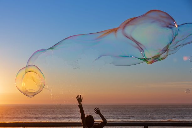 日落时分，人们在海滩上触摸着五颜六色的大泡泡图片下载