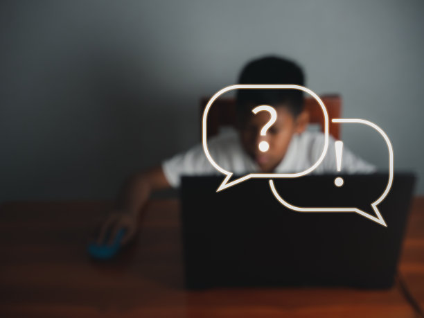 模糊的图片男孩坐在盯着笔记本电脑，他的手是握着鼠标与图标学习在前面。教育理念，教育信息搜索，复制空间图片下载