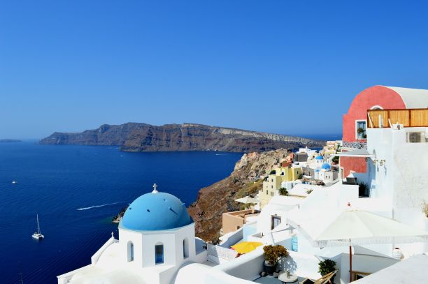 在希腊伊亚岛圣托里尼岛，蓝色圆顶教堂对着大海的美丽照片图片下载