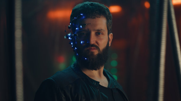 身穿黑色皮夹克、蓄着大胡子的年轻小伙子凶狠地盯着镜头——赛博朋克图片下载