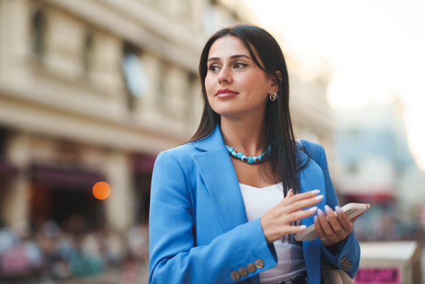 年轻女子拿着智能手机，在城市里四处张望图片下载