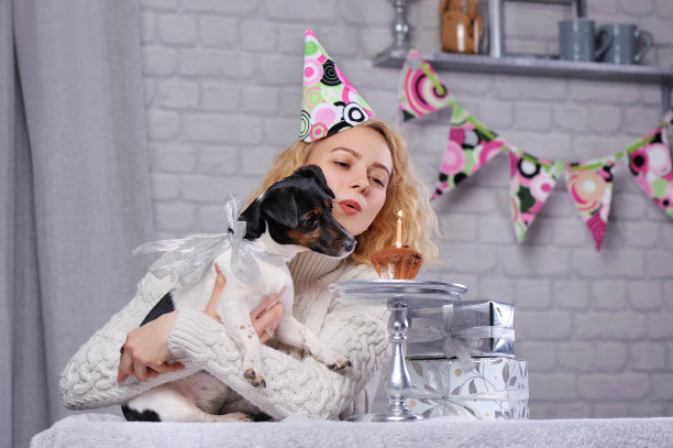 漂亮女孩带着她的杰克罗素梗吹生日蜡烛图片下载