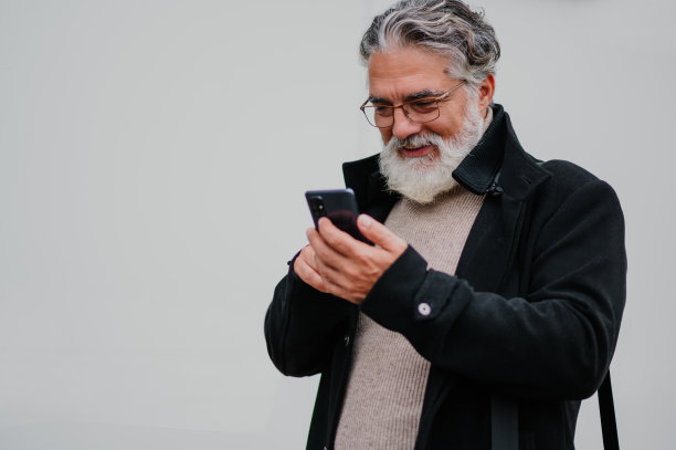 一名高级商人在办公楼外使用智能手机的画像图片下载