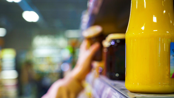 模糊的背景:一个女人的手从架子上拿了一罐果冻。图片下载