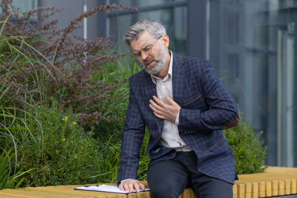 心痛的成熟男人，白发苍苍的商人牵着粗糙的手，心脏病发作的痛苦，老板在现代化写字楼外的长凳上，生病和劳累过度图片下载