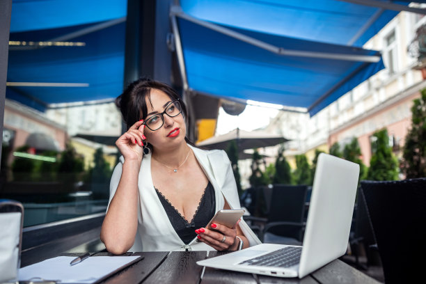 年轻的女商人在一个美丽的城市的露台上用笔记本电脑工作。图片下载