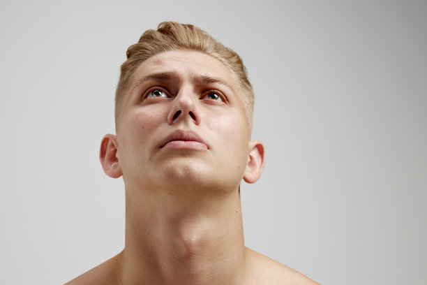 年轻男子的肖像摆赤膊孤立在灰色的工作室背景。向上看图片下载