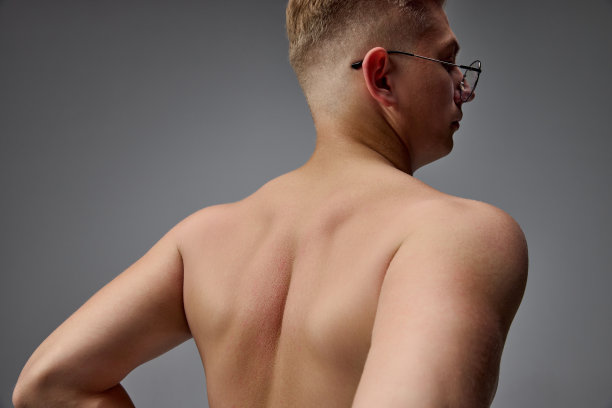 年轻肌肉男子的肖像摆姿势赤膊孤立灰色的工作室背景。背痛，脊椎痛。医疗按摩治疗图片下载