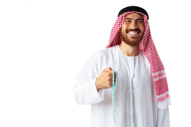 身着传统服装的年轻阿拉伯男子手持白色背景上孤立的珠子图片下载