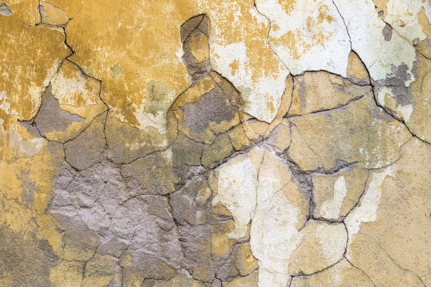 粗糙的、有补丁的、黄色的墙上有裂缝、破碎的混凝土纹理。关闭细节背景设计元素。图片下载