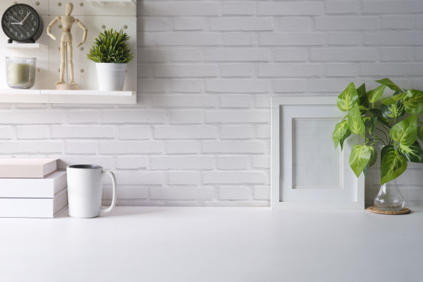 家庭办公室内部。室内植物，咖啡杯，书和铅笔架在白色的桌子上。图片下载