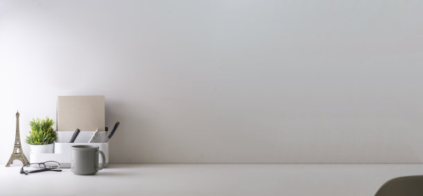 最小的工作场所，咖啡杯，铅笔架，笔记本和花盆在白色的桌子上。复制空间为您的广告文本。图片下载