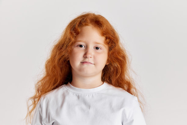 可爱的小女孩，长卷红色头发的孩子看着相机孤立在白色背景。观念儿童积极的情绪、美好的事物图片下载