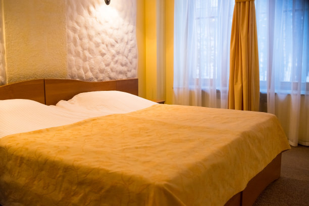 现代卧室，等待情侣。在优雅的卧室内部的床上黄色毯子。壁灯、灯具和舒适的家具。双人间，浅色，双人床。图片下载