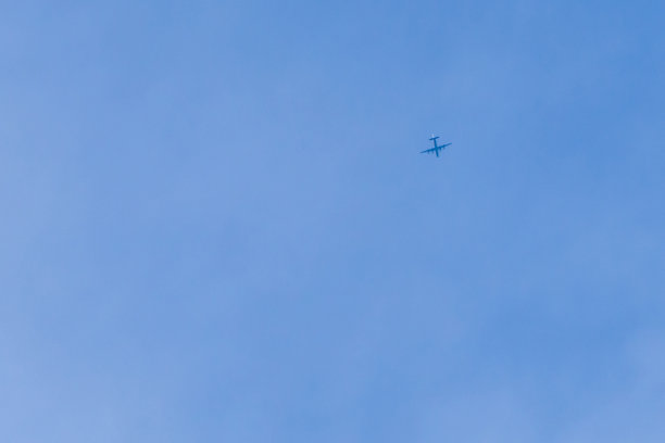 天空是蓝色的，带着一层浅白色的薄雾，飞机正高高飞着图片下载