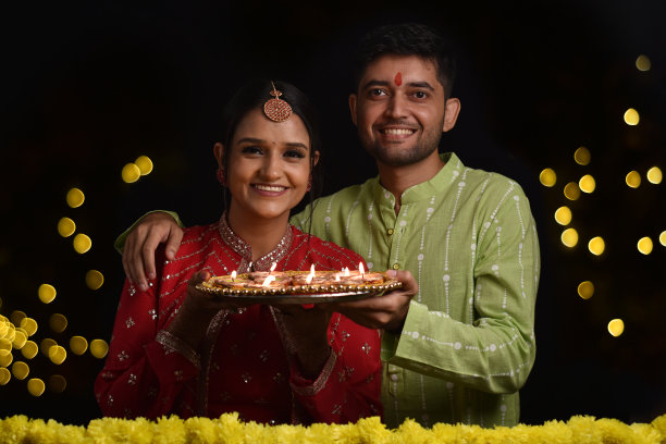 快乐的年轻夫妇庆祝排灯节，拿着一盘排灯节和糖果图片下载