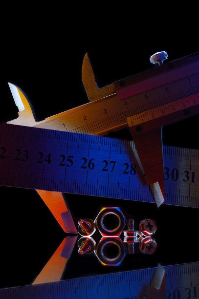 不同尺寸的镀铬金属螺母和测量螺母的卡尺。黑色背景。图片下载