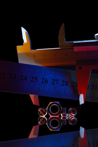 不同尺寸的镀铬金属螺母和测量螺母的卡尺。黑色背景。图片下载