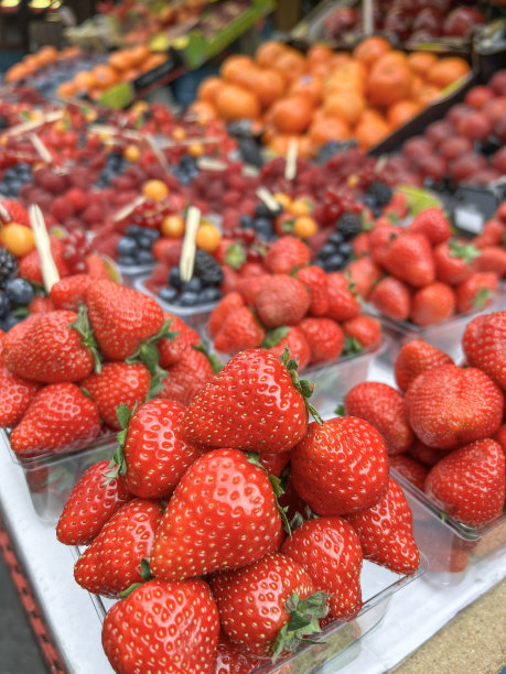 市场上，成熟的草莓堆在混合水果上图片下载