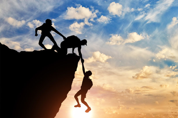 三个男性登山者营救另一个男性登山者拉他的手臂的剪影图片下载