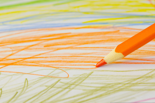 一支橙色的铅笔在一张纸上随意地画着图片下载