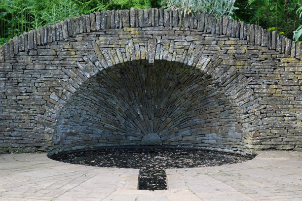 池塘或水池上的干石墙桥。海兰兹公园正式花园。图片下载