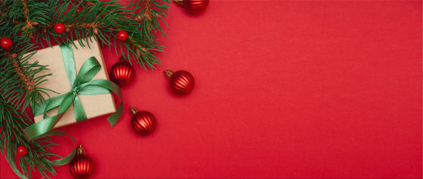云杉，冷杉枝，红色浆果，礼品盒在红色背景。帧边界。圣诞组成。空间的文本。横幅。图片下载
