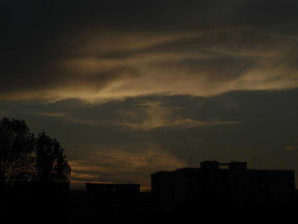 日落时，树木和建筑物的剪影映衬着多云的天空图片下载