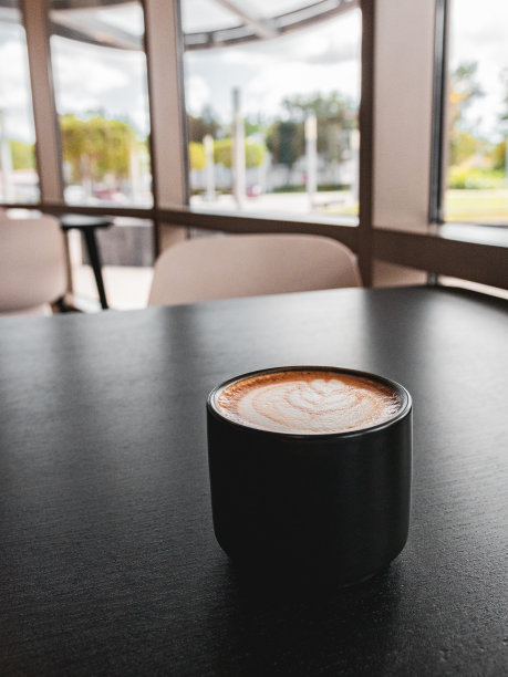 浓缩咖啡杯图片在黑色的桌子背景与心脏艺术混合牛奶。咖啡师的咖啡艺术，上面有拿铁牛奶。美味的咖啡壁纸。coffeshop和平环境。图片下载