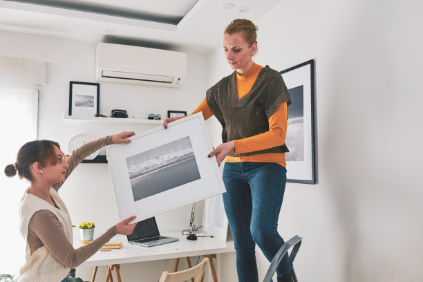 母女俩在家里挂图画和照片。图片下载