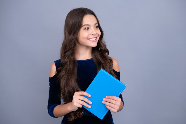 快乐微笑的少年女学生。学生，十几岁的学生女孩拿着书在灰色孤立的工作室背景。学校和教育理念。回到学校。图片下载