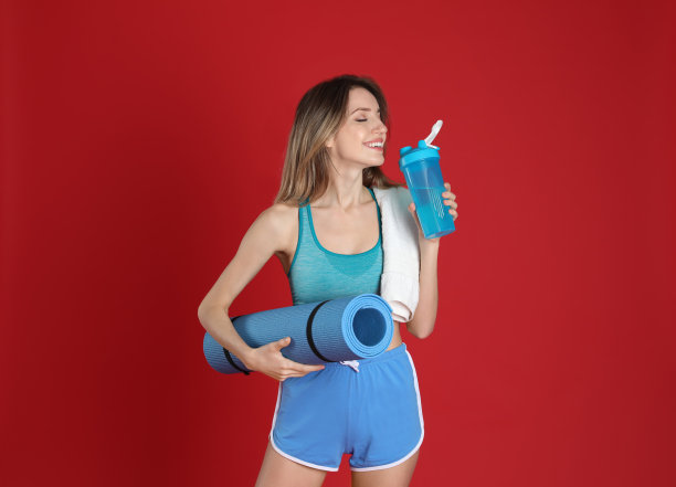 美丽的女人与瑜伽垫，毛巾和摇床上的红色背景图片下载