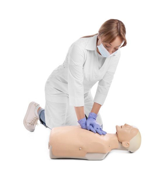 身穿制服、戴口罩的医生在白色背景的人体模型上练习急救图片下载
