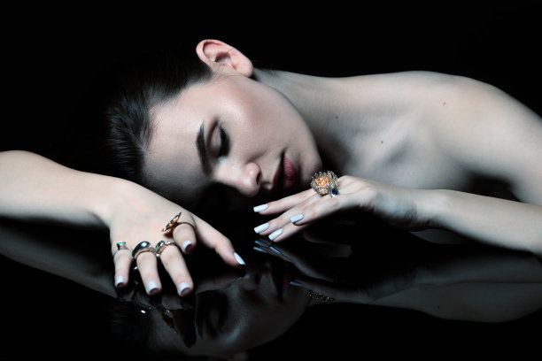 工作室的美丽和性感的褐发女人与花哨的化妆和各种戒指在她的手指肖像图片下载