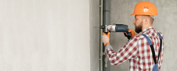 工人建筑工工作穿孔与大长钻，钻混凝土墙，在白色背景。维修服务和施工理念。横幅图片下载